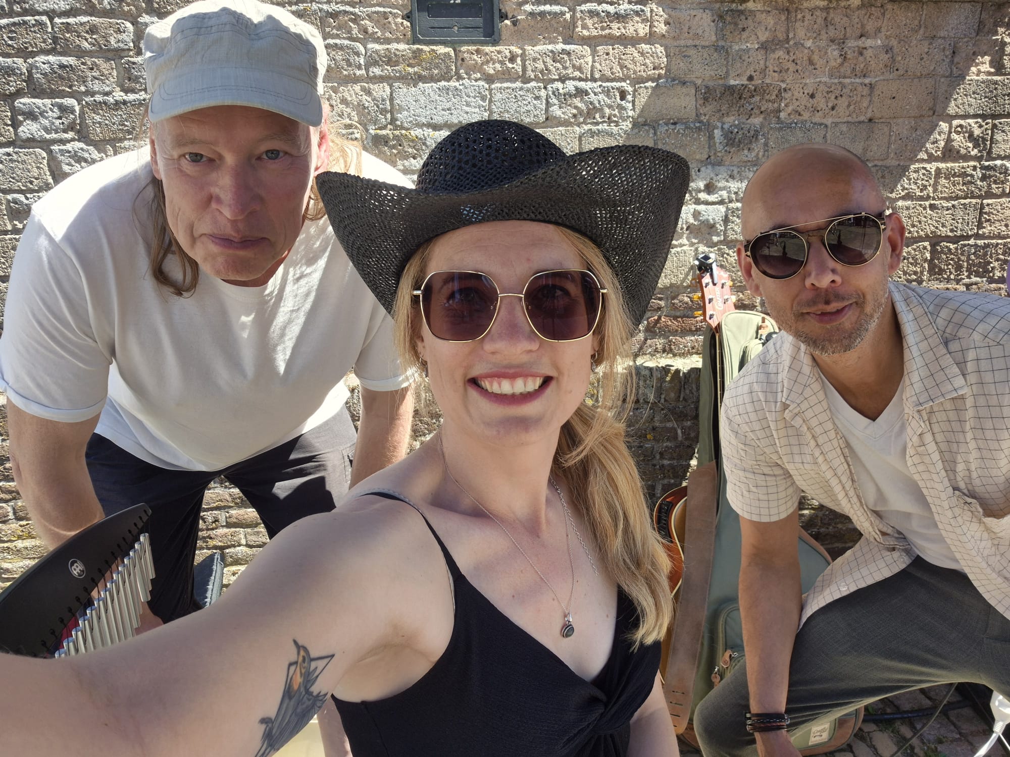 een vrouw met cowboyhoed en 2 mannen erachter geposeerd
