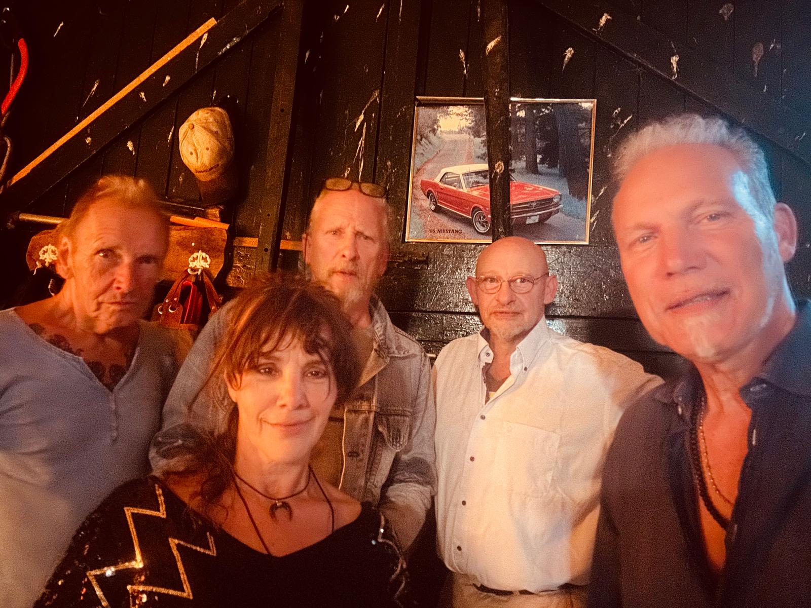 5 personen kijken blij met een old timer op de achtergrond
